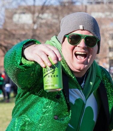 Runner in a green shamrock costume enjoying a finish line beer at the 2026 Philly Shamrock Run