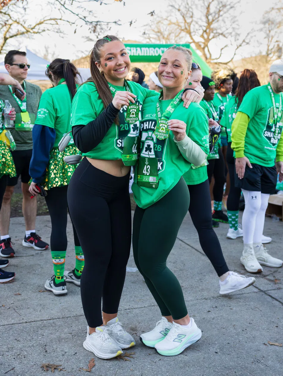 Two Philly Shamrock Run finishers proudly holding their 2026 finisher medals