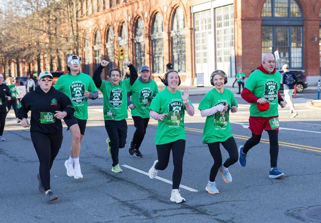 Happy Philly Shamrock Run participants running through the Navy Yard in green race shirts